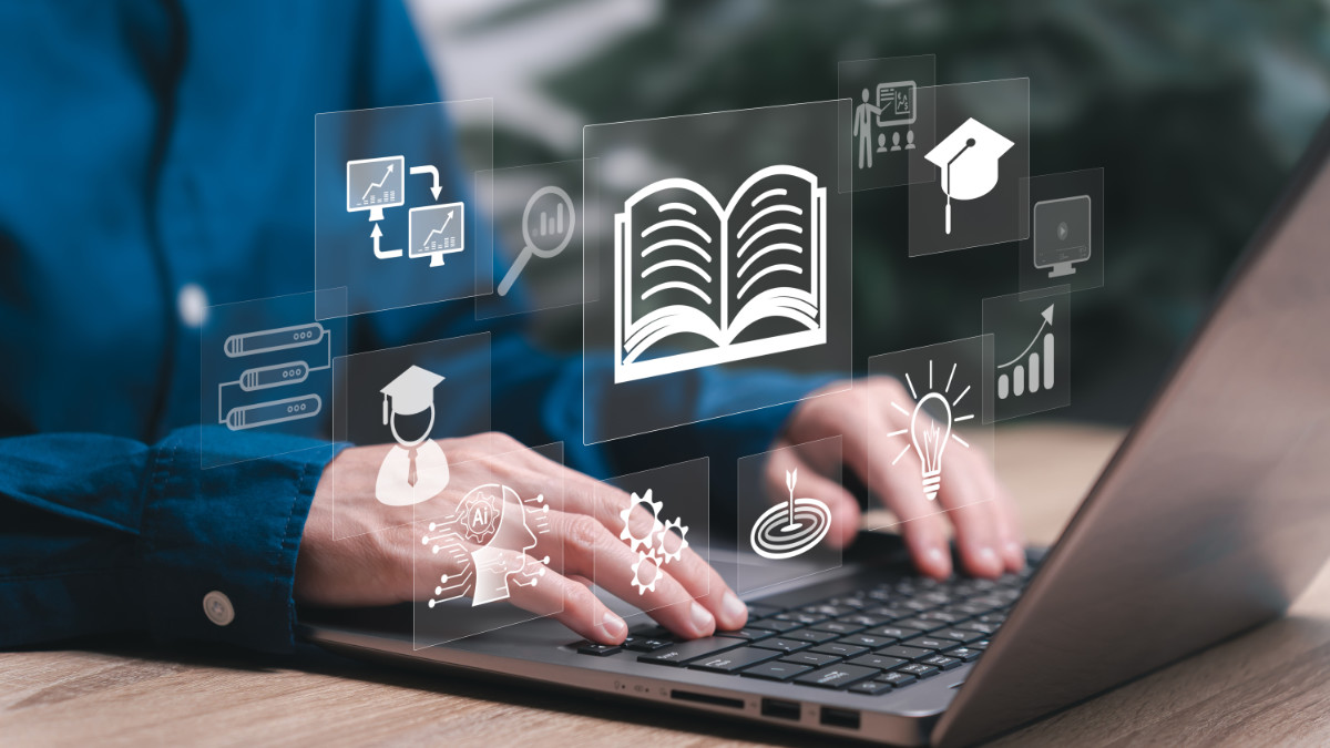 Mężczyzna siedzi przy laptopie. Nad klawiaturą unosza się ikonki związane z edukacją
